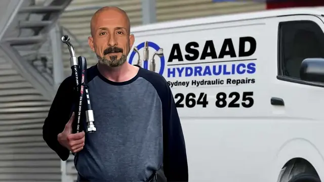 An Asaad Hydraulics team member with two hoses in front of the van